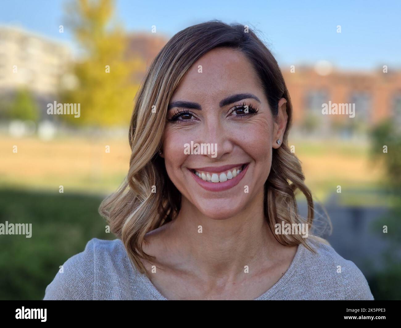 Glückliche Frau mittleren Alters in einem Stadtpark. Attraktive Frau lächelt zur Kamera. Stockfoto