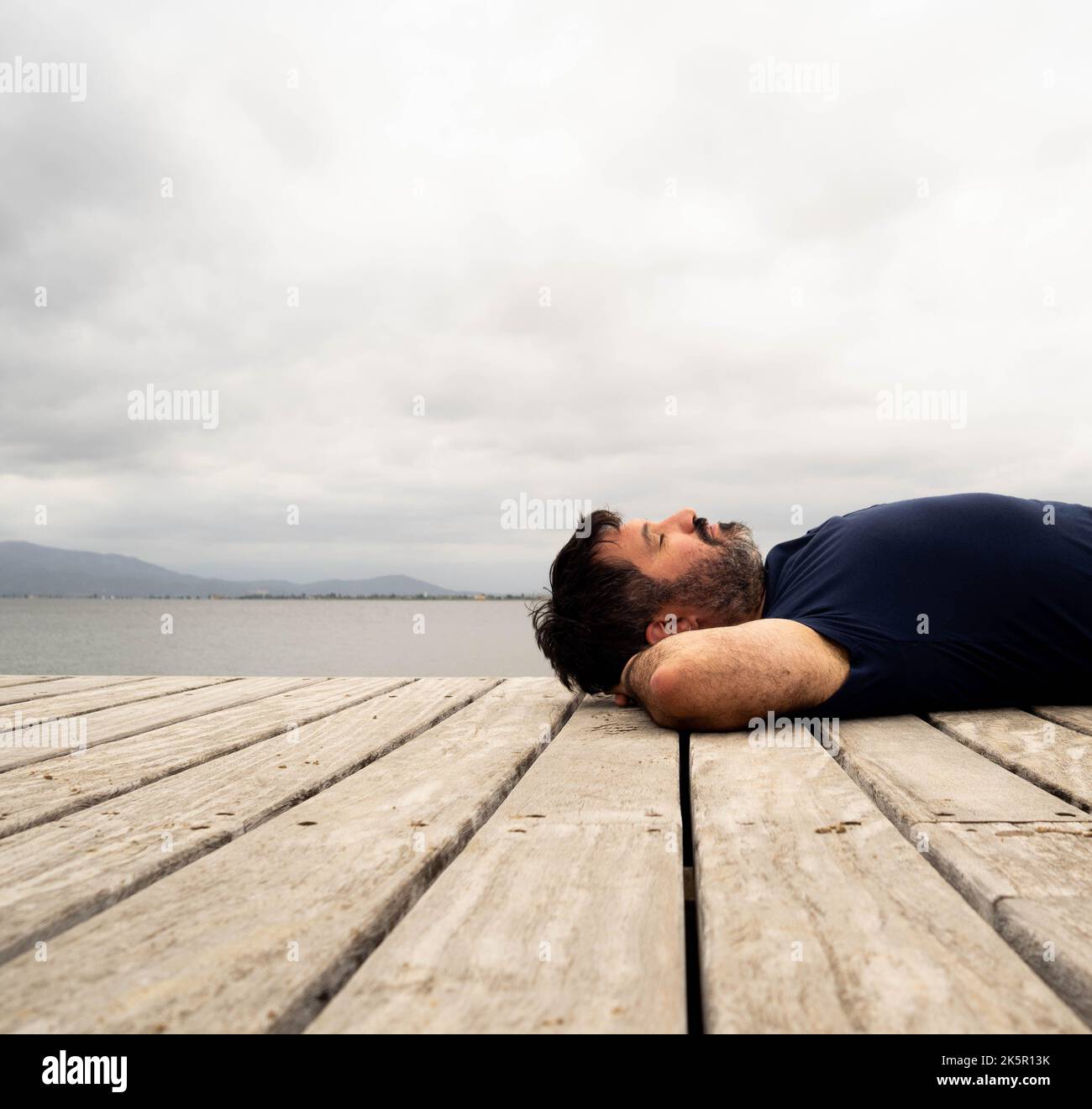 Junger Mann, der mit geschlossenen Augen in der Natur liegt. Konzept der Entspannung in der Natur Stockfoto