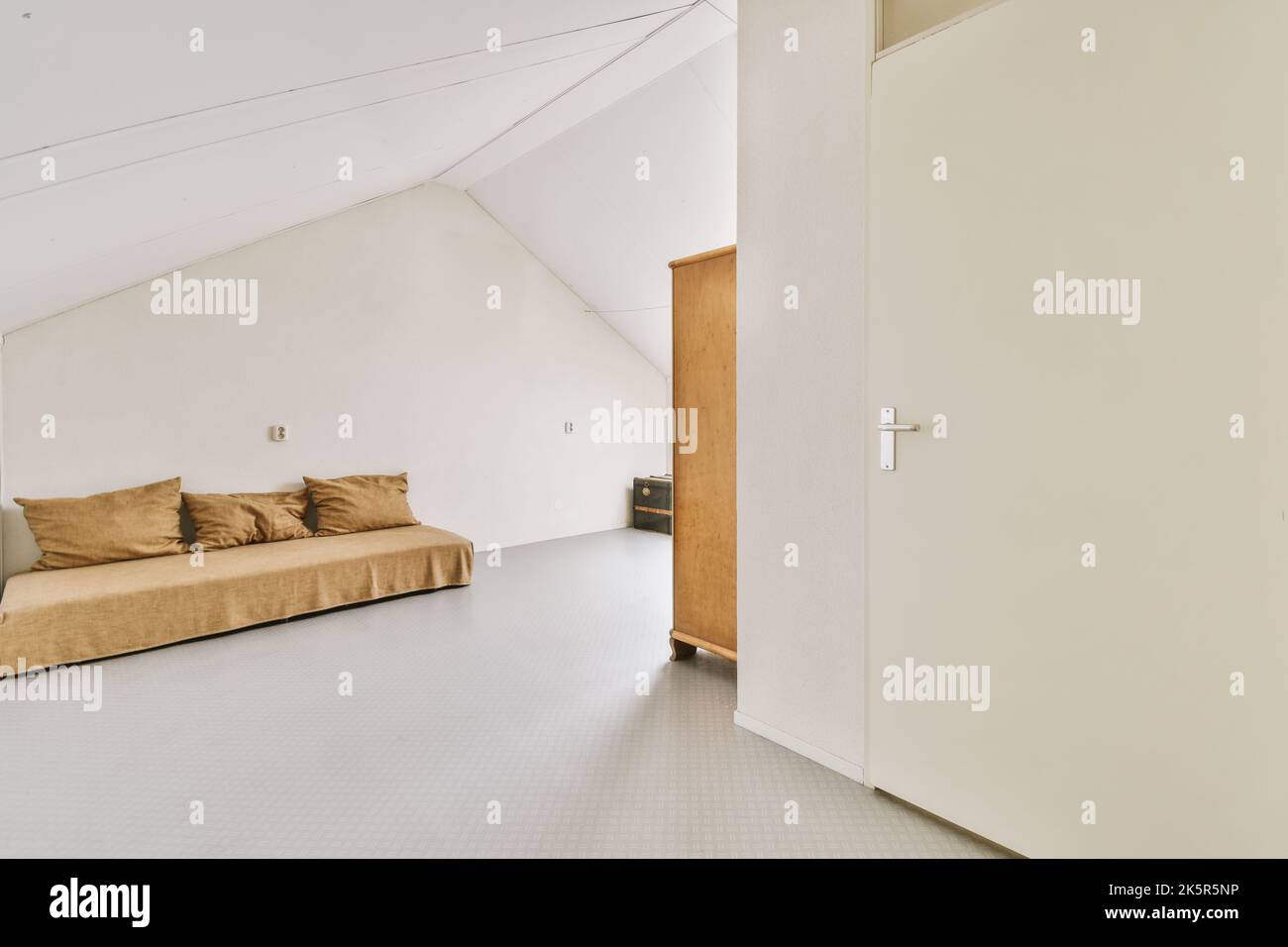 Gemütliches Interieur Design des Wohnzimmers mit komfortabler Couch und Holztisch dekoriert Lampe in modernen Dachgeschoss-Wohnung mit weißen Wänden und Säule eingerichtet Stockfoto