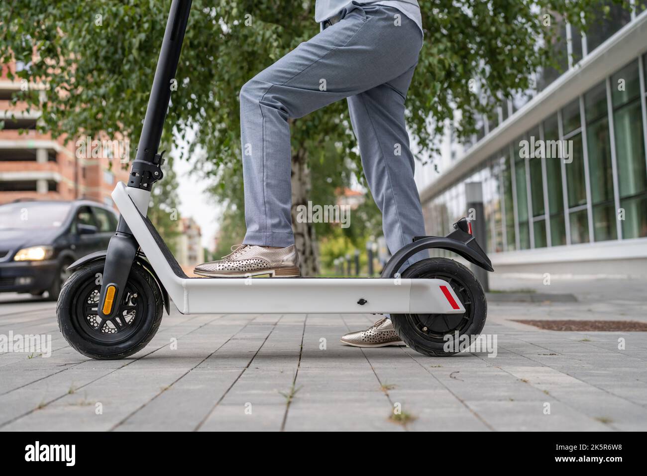Füße von unbekannten Frau stehen oder fahren Elektro-Kick Scooter E-Scooter auf dem Bürgersteig am Tag umweltfreundliche moderne Transport in der Stadt oder Stadt Stockfoto