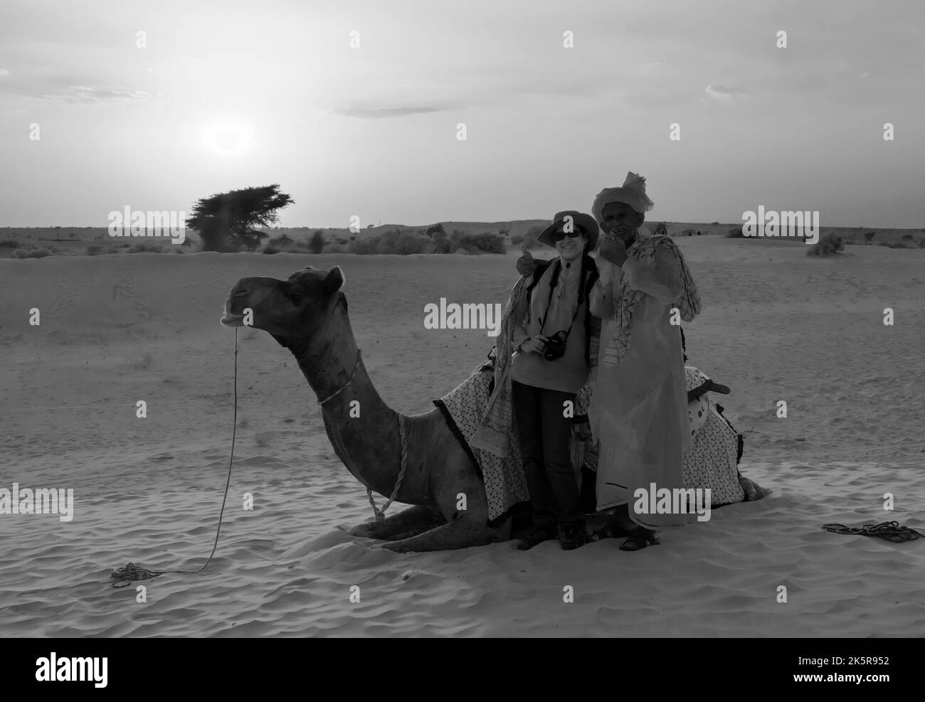 Thar Desert,Rajasthan,India-15. October 2019 : Cameleer und eine indische Touristenfotografin posieren mit Kamel, Sonnenuntergang in Sanddünen. Nocken Stockfoto