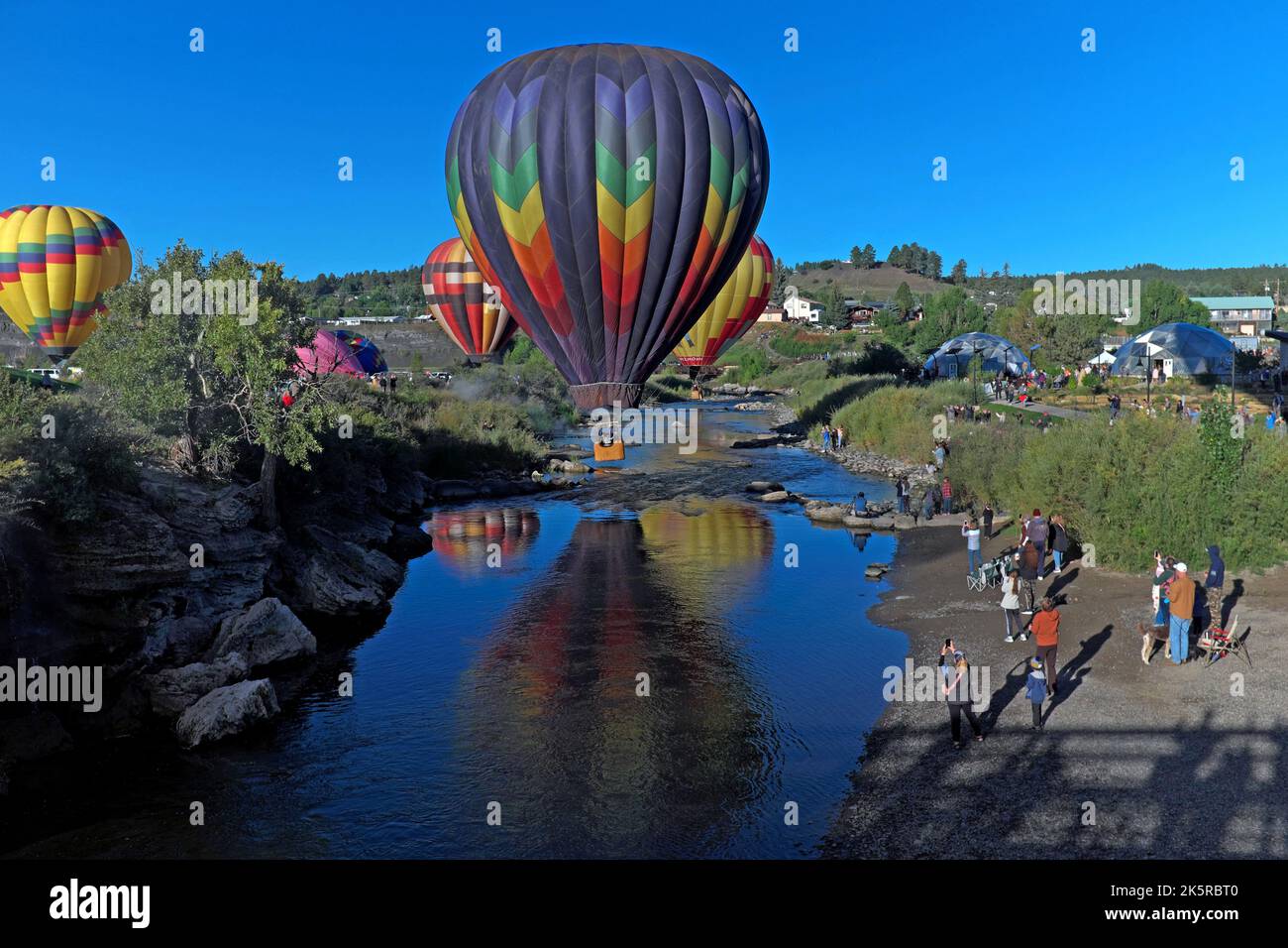 Farbenfrohe Heißluftballons fliegen während der Colorfest Balloon Rally 2022 über den San Juan River in Pagosa Springs, Colorado, in den Himmel. Stockfoto