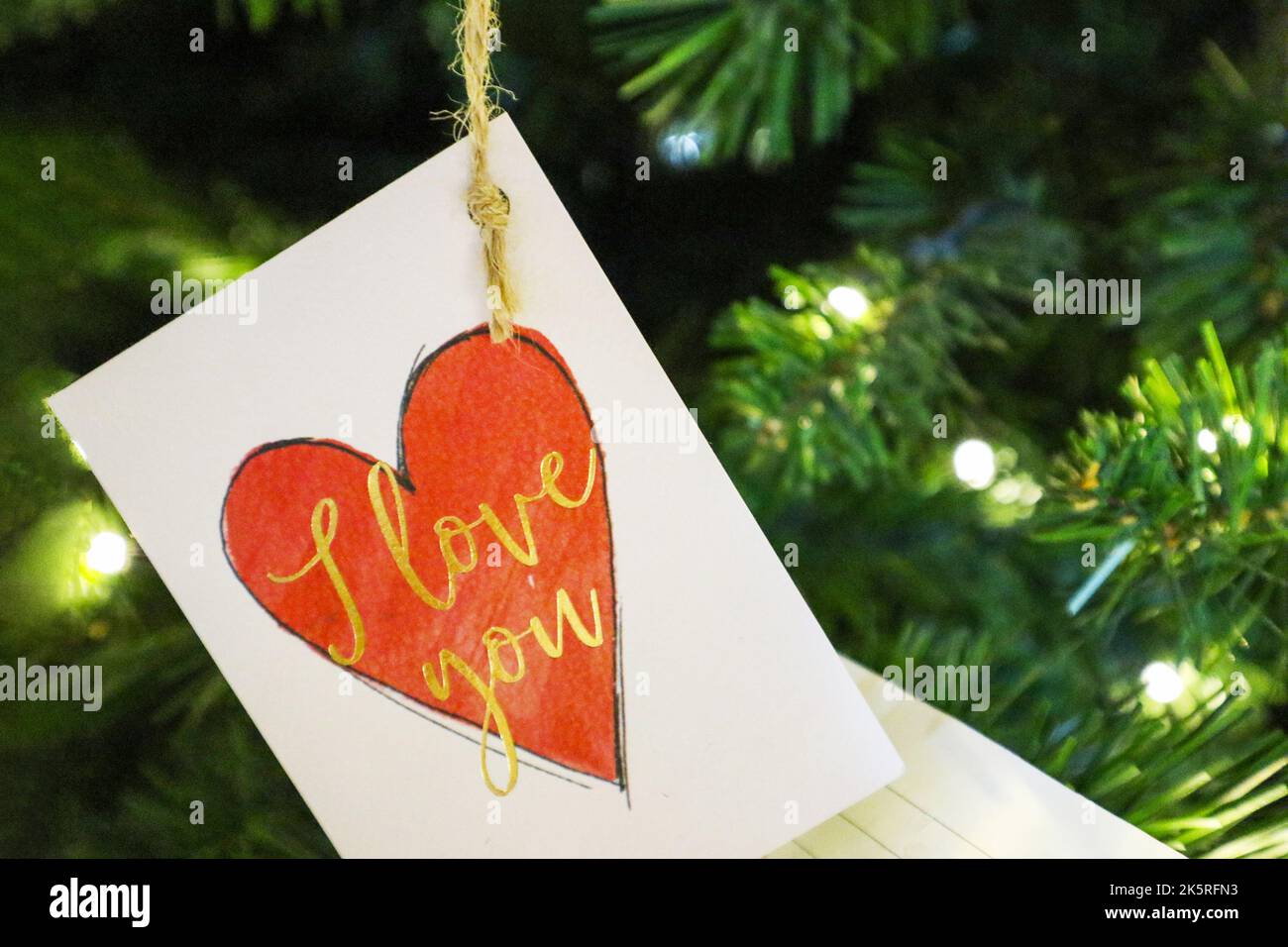 Ich liebe Sie Postkarte auf dem Weihnachtsbaum. Postkarten und Laternen auf dem Weihnachtsbaum für den Feiertag.Botschaft des neuen Jahres Stockfoto