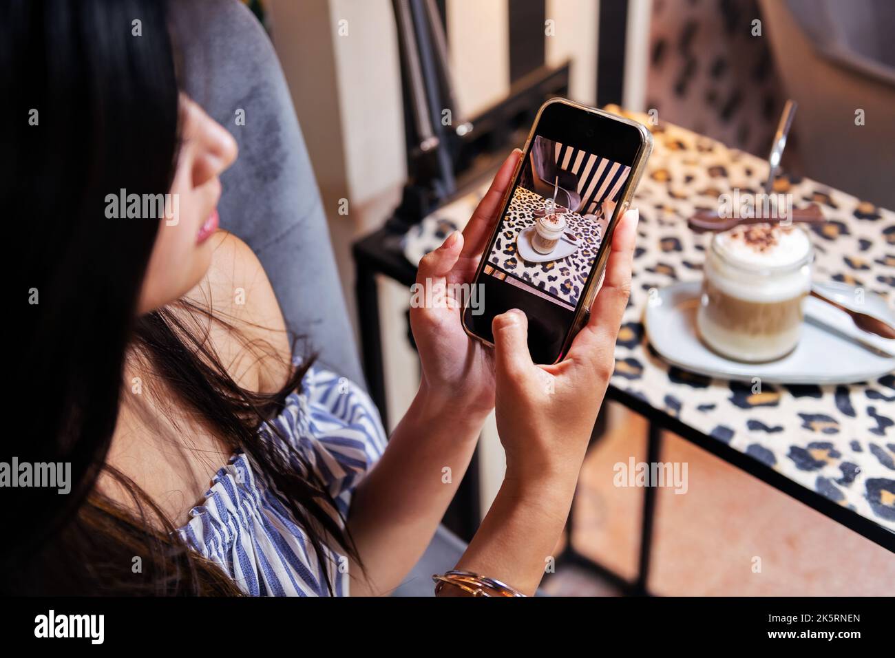 Frau, die mit ihrem Telefon ein Foto von ihrem Kaffee machte Stockfoto