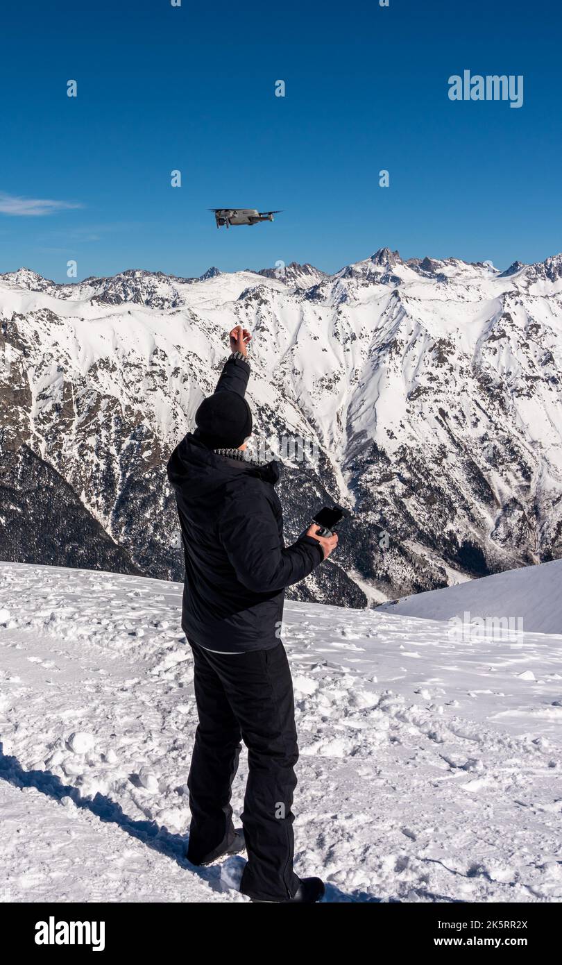 Drohne, die im Winter von der männlichen Hand auf dem Gipfel des verschneiten Berges abheben Stockfoto