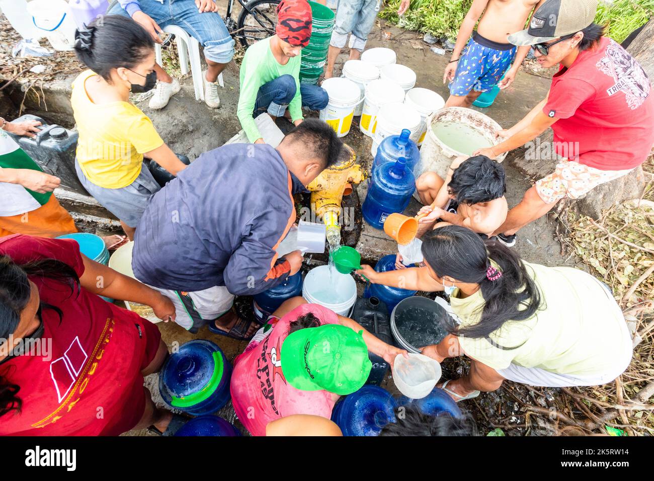Menschen, die Wasser von einem Hydranten aufgrund eines Wassermangels erhalten, der vom Taifun Odette in Cebu City, Philippinen, gebracht wurde Stockfoto