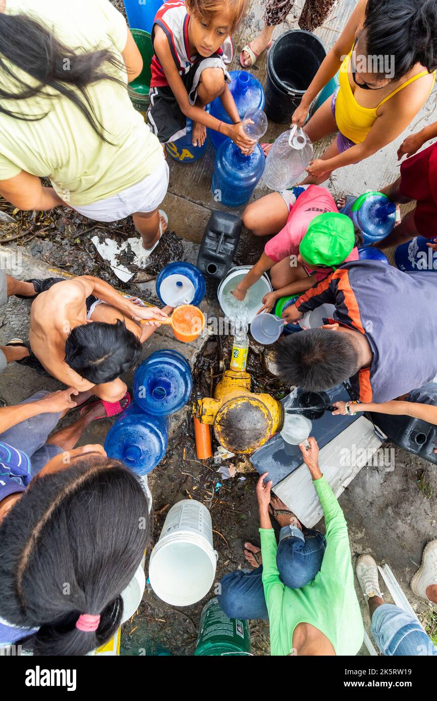 Menschen, die Wasser von einem Hydranten aufgrund eines Wassermangels erhalten, der vom Taifun Odette in Cebu City, Philippinen, gebracht wurde Stockfoto
