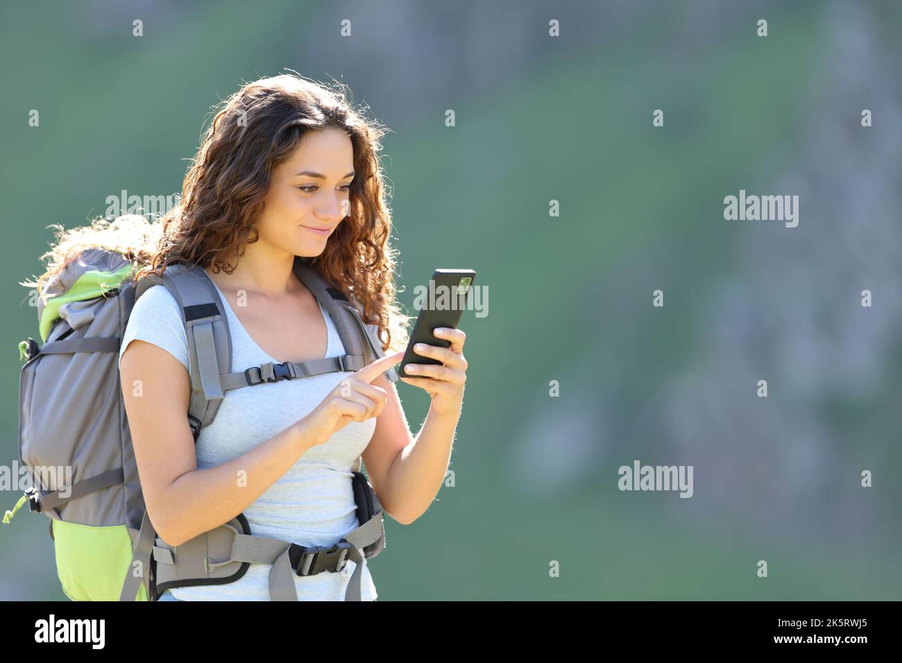 Glücklicher Wanderer, der mit dem Smartphone in den Berg läuft Stockfoto