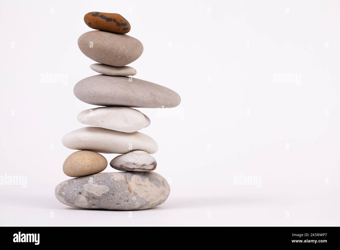 Säule aus Buchensteinchen isoliert auf weißem Studiohintergrund. Zen-Entspannungskonzept Stockfoto