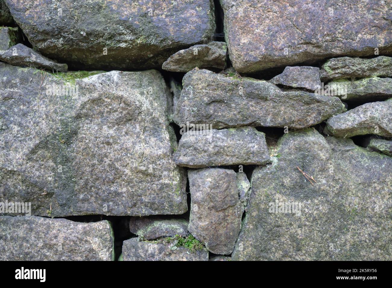 Detail einer Steinmauer, die einen Haufen in einem ehemaligen Granodiorit-Steinbruch hält. Trockene Wand aus Steinen verschiedener Größen, einfache alte indostiral Architektur gebaut. Stockfoto