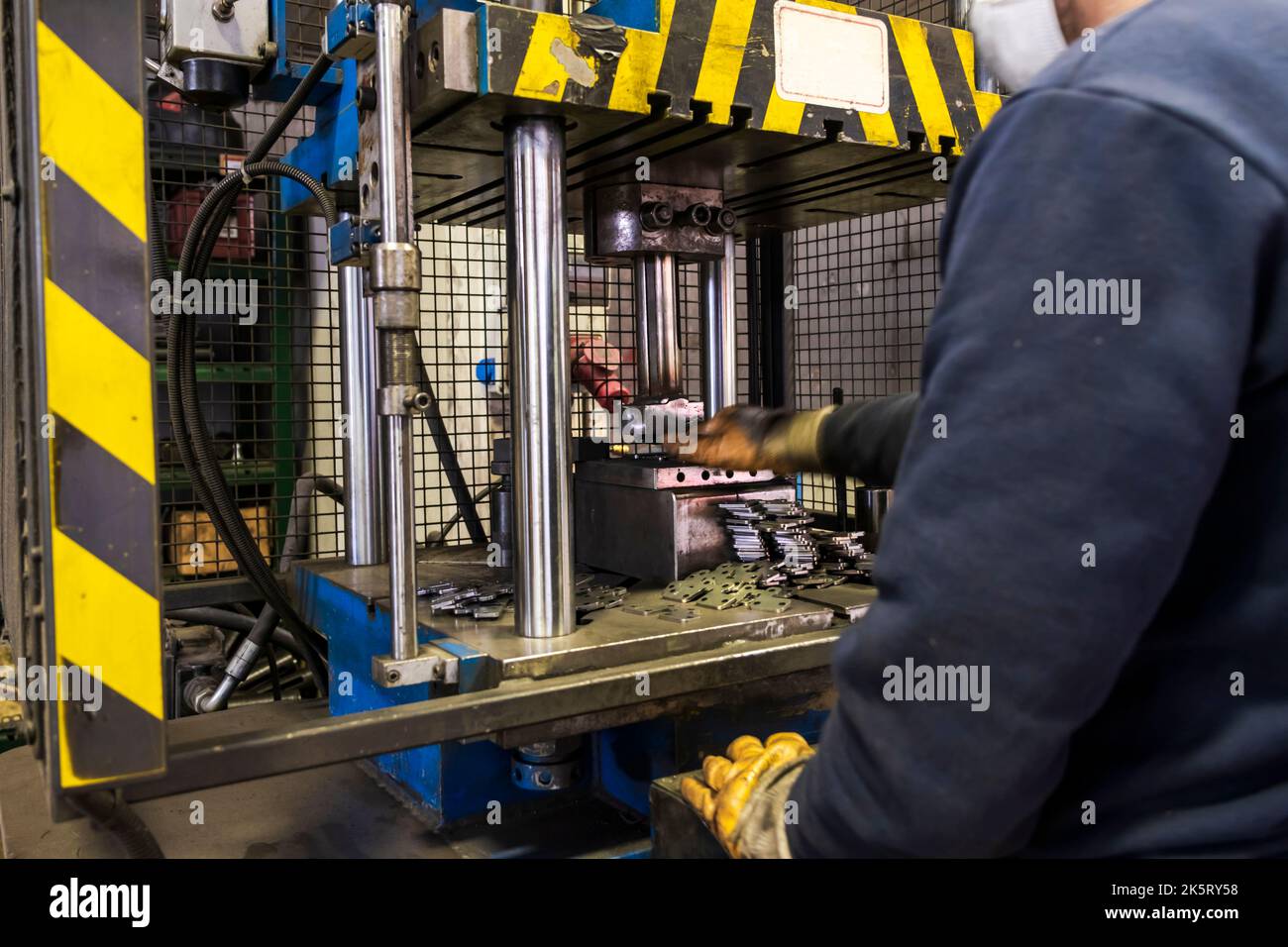 Automatisierung hydraulische Presse Stanzmaschine Produktionslinie. Industrielle Metallbearbeitungsmaschinen. Ein Arbeiter drückt einen Stempel in einer Hydraulikpresse. Stockfoto