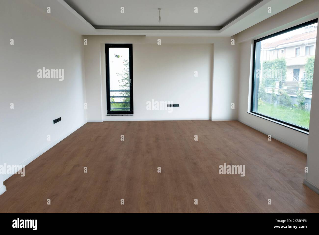 Leerer Innenhintergrund, Zimmer mit weißen Wänden, großen und kleinen Fensterböden, gefliestes Parkett. Stockfoto