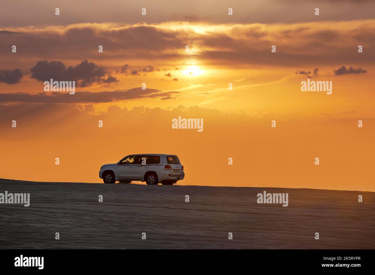 Toyota Landcruiser 4WD Fahrt durch Dünen bei Sonnenuntergang Zeit. Düne Bashing als Teil einer Wüstensafari in Katar Stockfoto