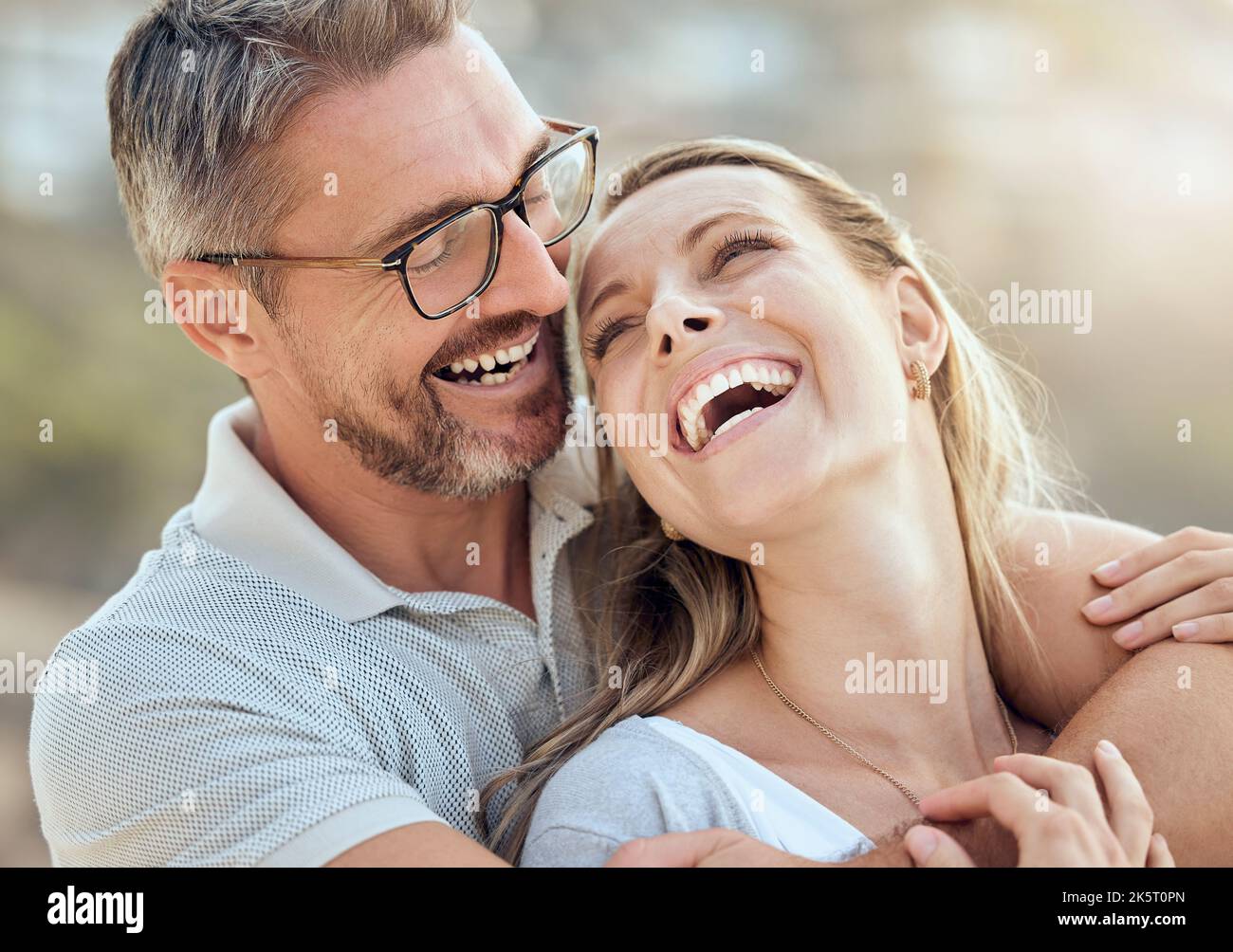 Glückliches und liebevolles reifes kaukasisches Paar, das an einem sonnigen Tag gemeinsam am Strand ein romantisches Date genießt. Fröhlicher, liebevoller Mann, der sich am Arm umarmte Stockfoto