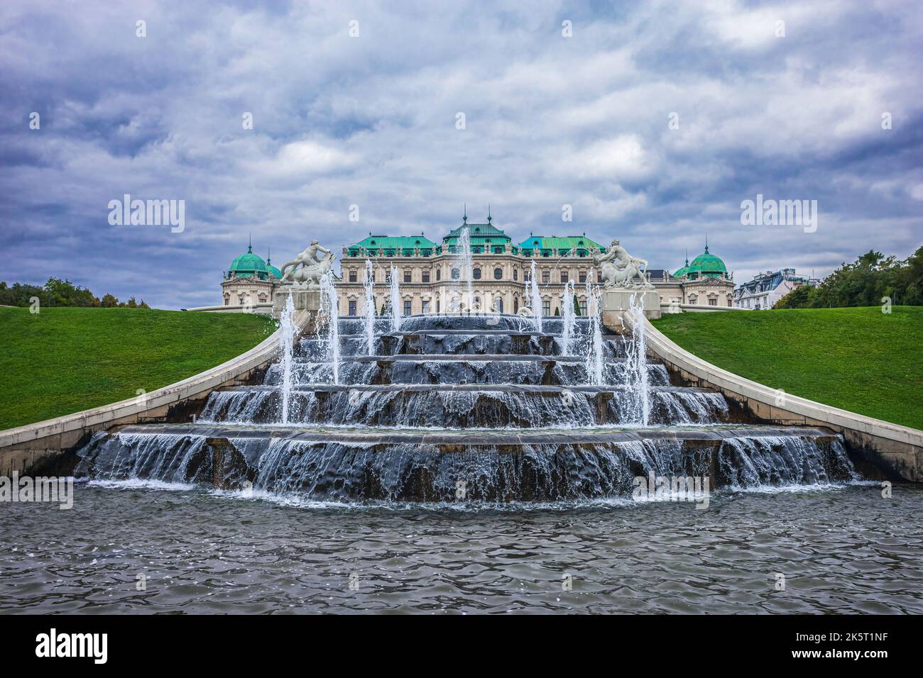 Brunnen im Belvedere Garten. Im Hintergrund erhebt sich das Schloss Oberes Belvedere vor stürmischem Himmel. Foto aufgenommen am 17.. September 2022 in Vienn Stockfoto