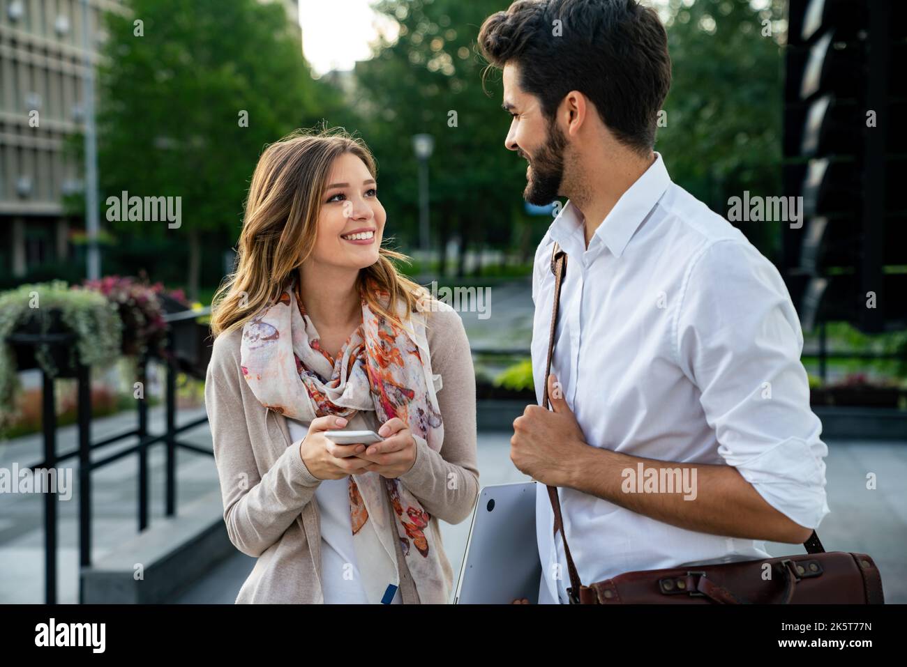 Glückliche junge Geschäftsleute, die im Freien chatten und digitale Geräte nutzen Stockfoto