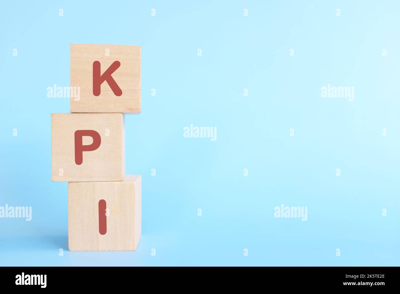 KPI oder Key Performance Indicator Business Target und Establishment Concept. Menschliche Hand stapelt Holzblöcke auf blauem Hintergrund. Stockfoto
