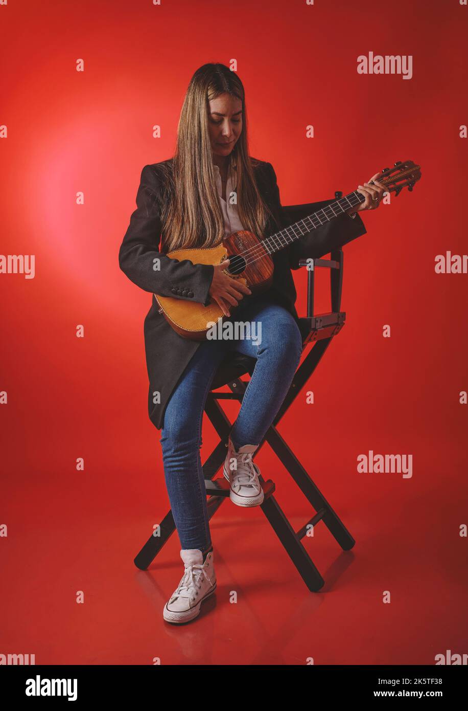 Schöne junge Frau, die ein CUATRO spielt, ein typisch venezolanisches Instrument. Aufnahmesession, Konzept der Musik und typische Instrumente. Stockfoto