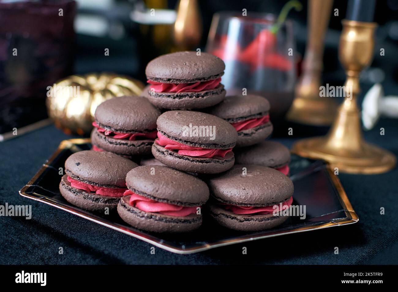 Braune Schoko-Makronen mit rosa Füllung. Waldbeeren in Cremefarben. Stockfoto