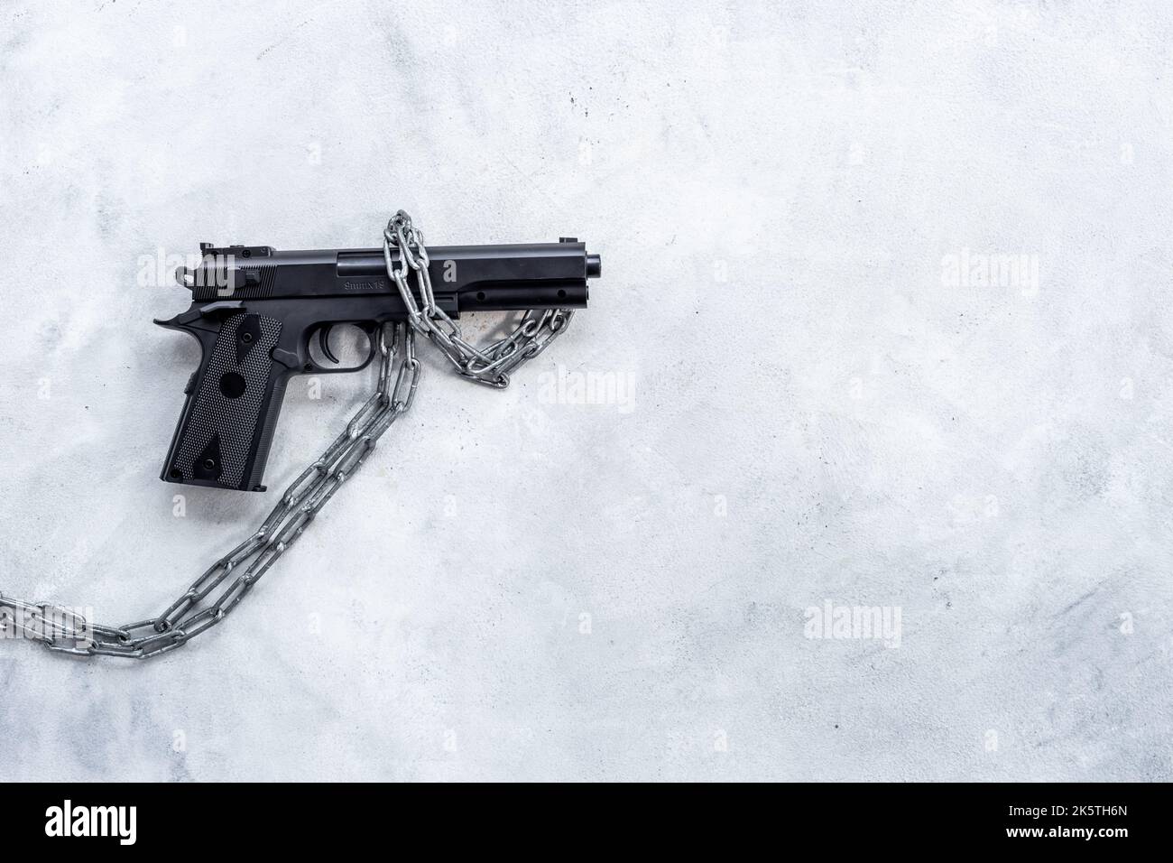 Schwarze Waffe in Ketten. Konzept des illegalen Einsatzes von Waffen Stockfoto