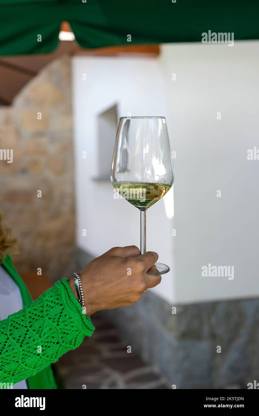 Die Hand der Frau hält ein Glas Weißwein. Nahaufnahme Stockfoto