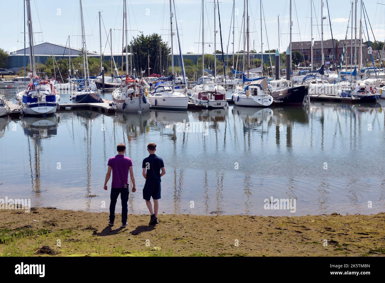 Zwei junge Männer, die festgetäute Segelboote betrachten, lowestoft suffolk england Stockfoto