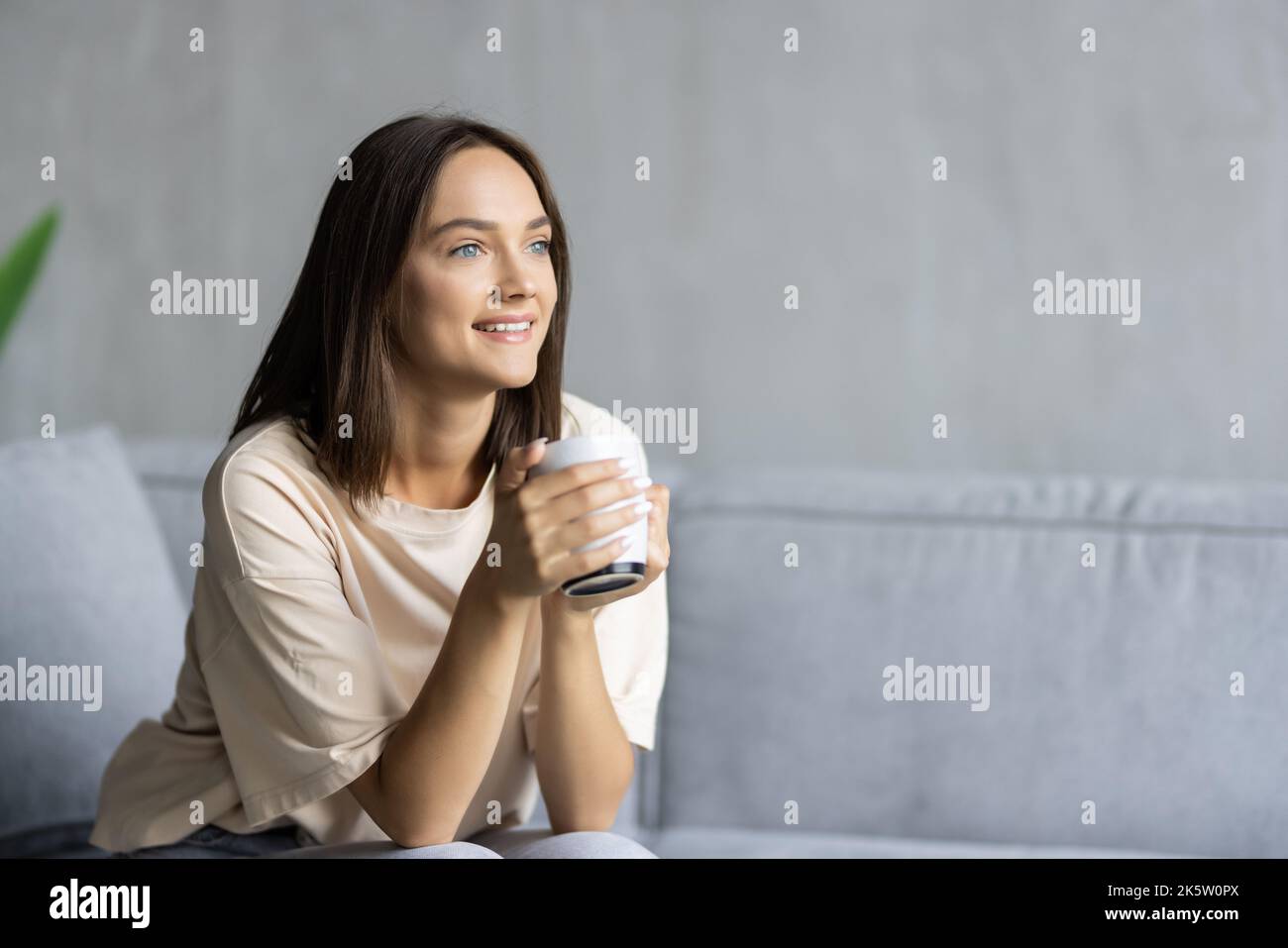 Porträt einer schönen aukasianischen jungen Frau, die auf dem Sofa sitzt Stockfoto