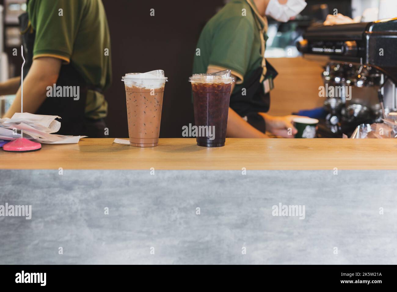 Oben auf der Theke gab es einen eisgekühlten Kaffee mit einem Barista, der im Hintergrund im Café arbeitete. Stockfoto