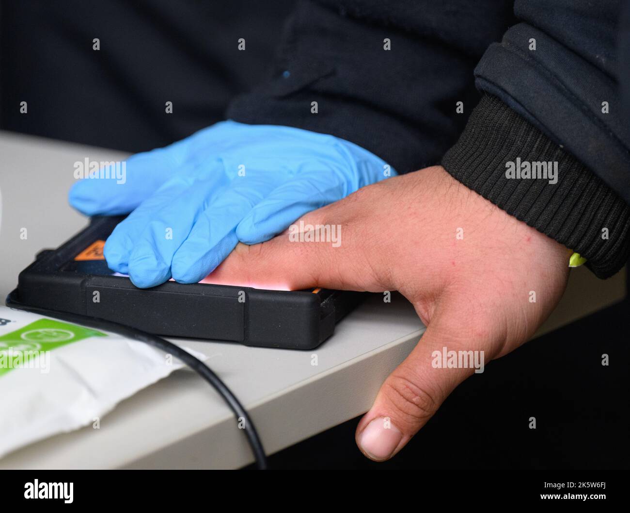 Dresden, Deutschland. 10. Oktober 2022. Ein Flüchtling aus Syrien wird bei der Registrierung am PIK-Bahnhof (Personalisierungs-Infrastrukturkomponenten) im Ankunftsbereich für Flüchtlinge am Hauptbahnhof abgedruckt. Kredit: Robert Michael/dpa/Alamy Live Nachrichten Stockfoto