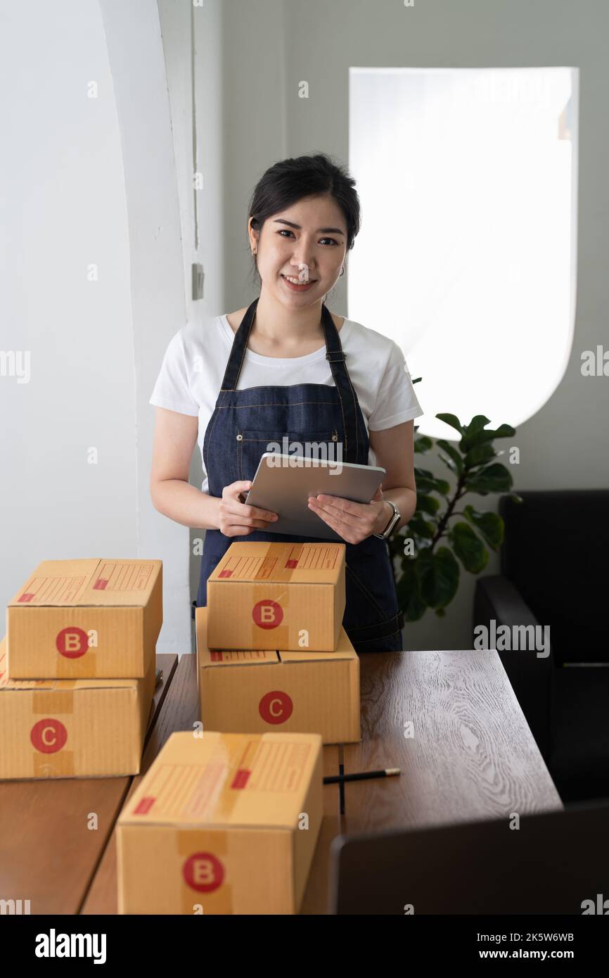Portrait junger asiatischer Kleinunternehmer zu Hause, Online-Marketing-Verpackungs- und Lieferszene, Startup-KMU-Unternehmer oder freiberuflicher Mitarbeiter Stockfoto