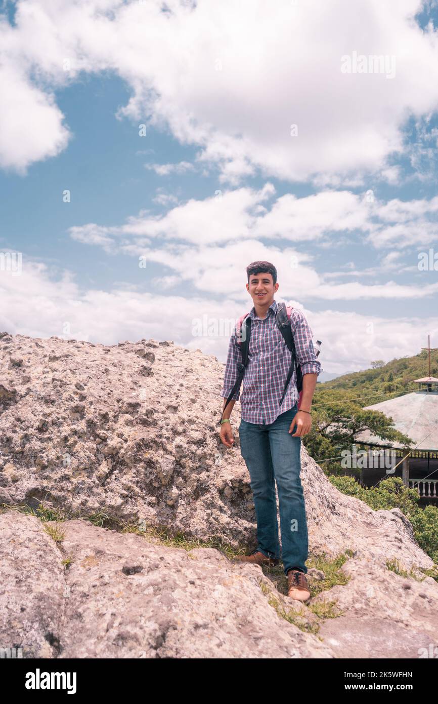 Ein lateinischer Teenager auf einem Felsen, der lächelt und in die Kamera schaut Stockfoto