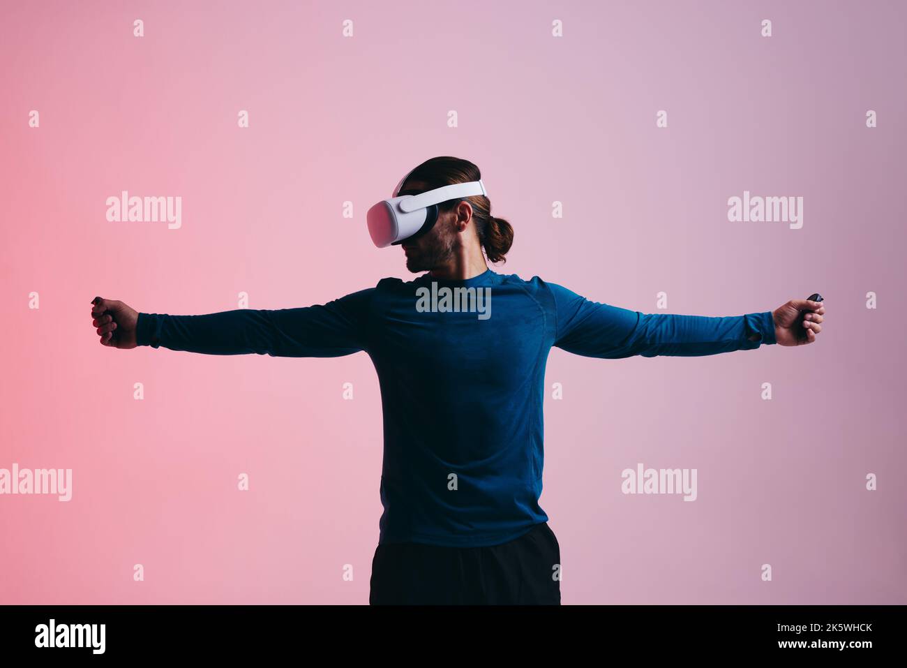 Junger Mann spielt ein Virtual-Reality-Shooting-Spiel. Junger Mann, der mit ausgestreckten Armen steht und ein Virtual-Reality-Headset trägt. Mann explorin Stockfoto
