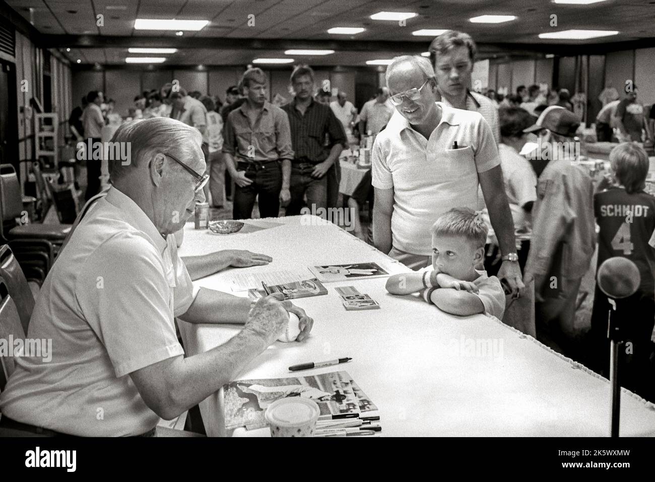 Ein Junge, der Ehrfurcht vor dem Pitcher der Baseballhalle Bob Feller hat, der Autogramme bei einer Baseballkarte und einer Ausstellung mit Erinnerungsstücken aus dem Sport in Bismarck, ND, 1987, signiert Stockfoto