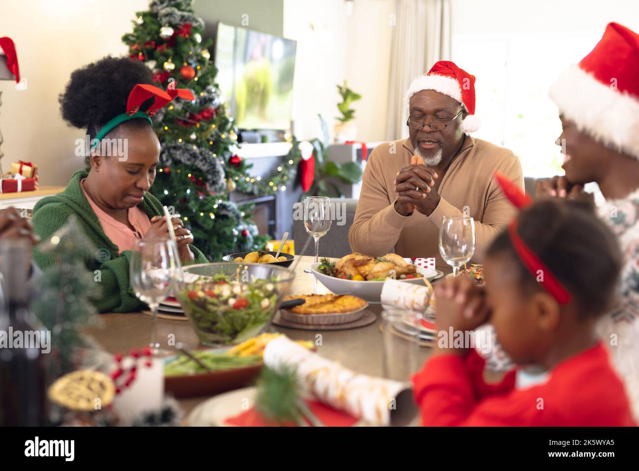 Die afroamerikanische Familie verbringt Zeit miteinander und betet vor dem weihnachtsessen Stockfoto