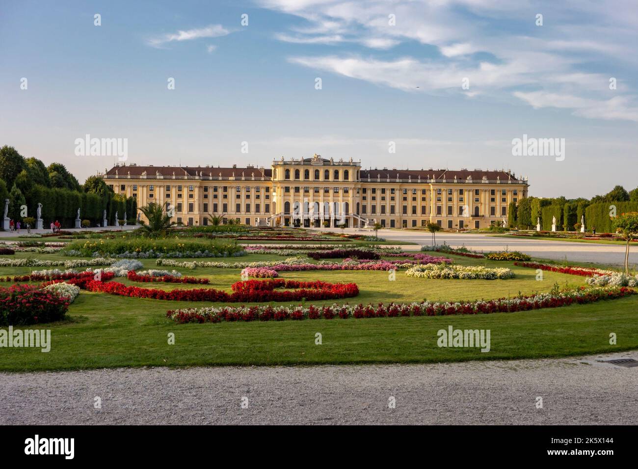 WIEN, ÖSTERREICH - 27. JULI 2021: Landschaft eines Parks und Schloss Schönbrunn in Wien, Österreich bei Sonnenuntergang mit Blumengärten Stockfoto