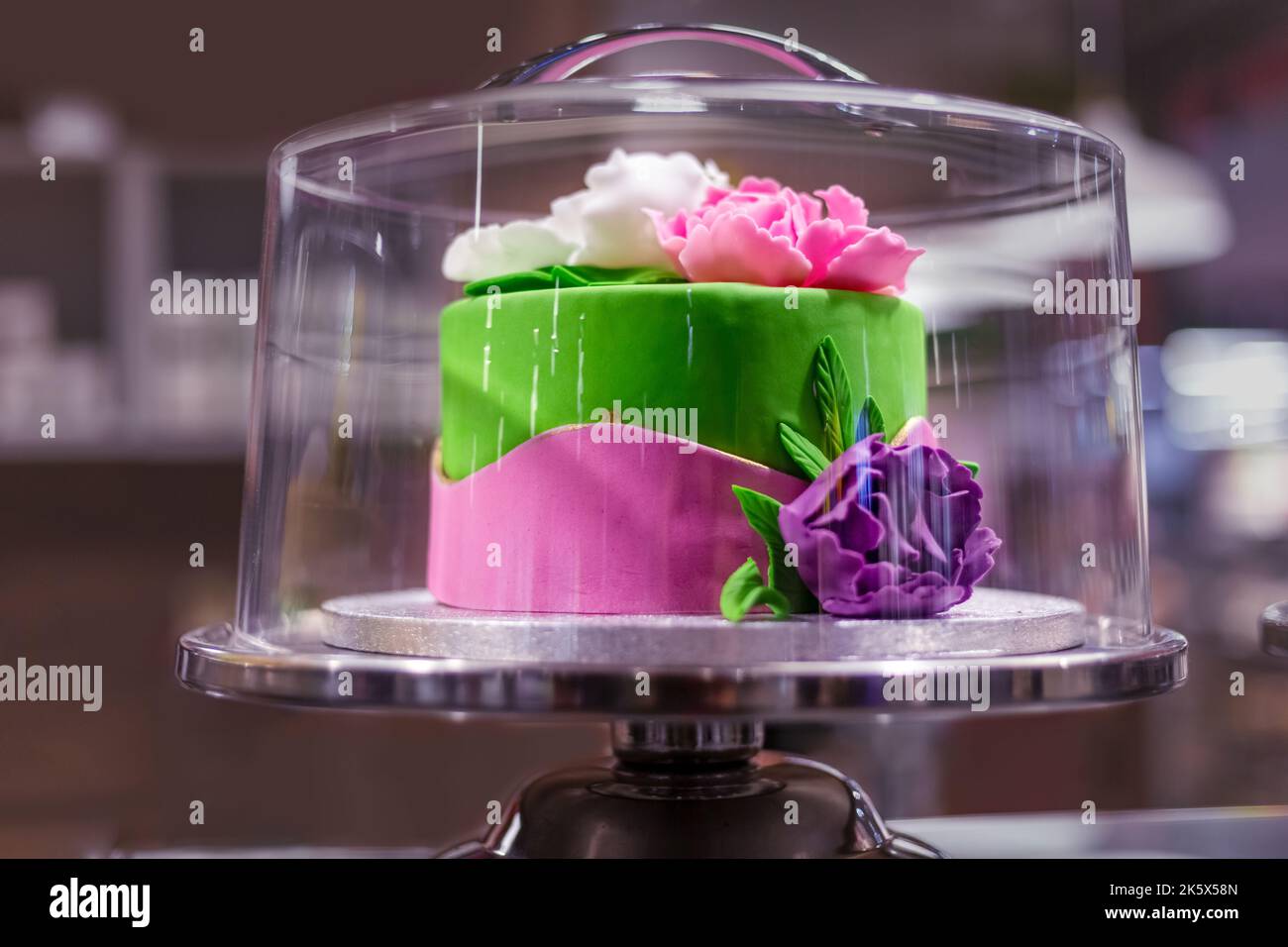 Elite-Kuchen mit Blumen in einer Glaskonditorei Vitrine dekoriert. Stockfoto