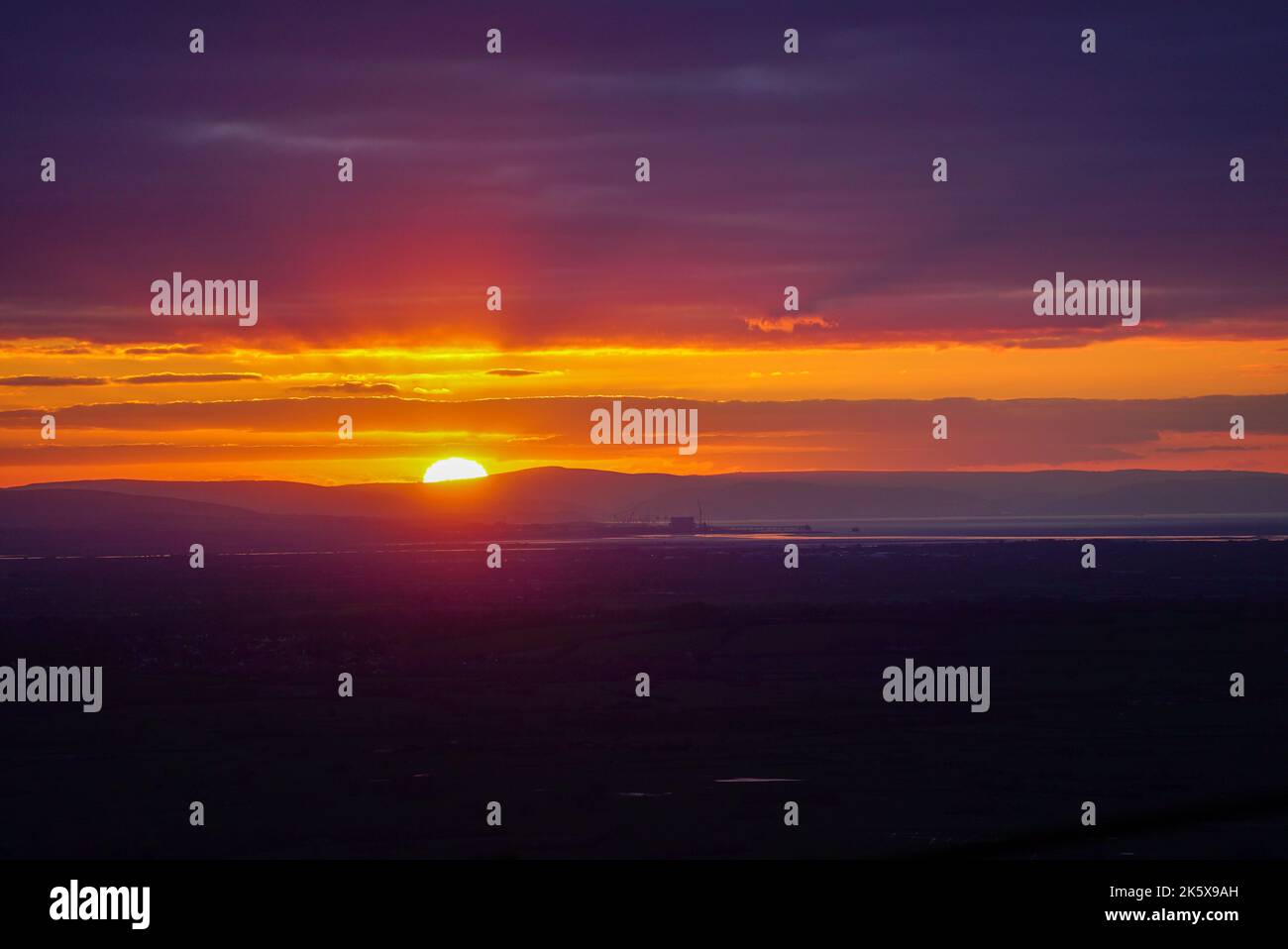 Sonnenuntergang mit crepuskulären Strahlen über dem EDF Energy Hinkley Point Kraftwerk Stockfoto