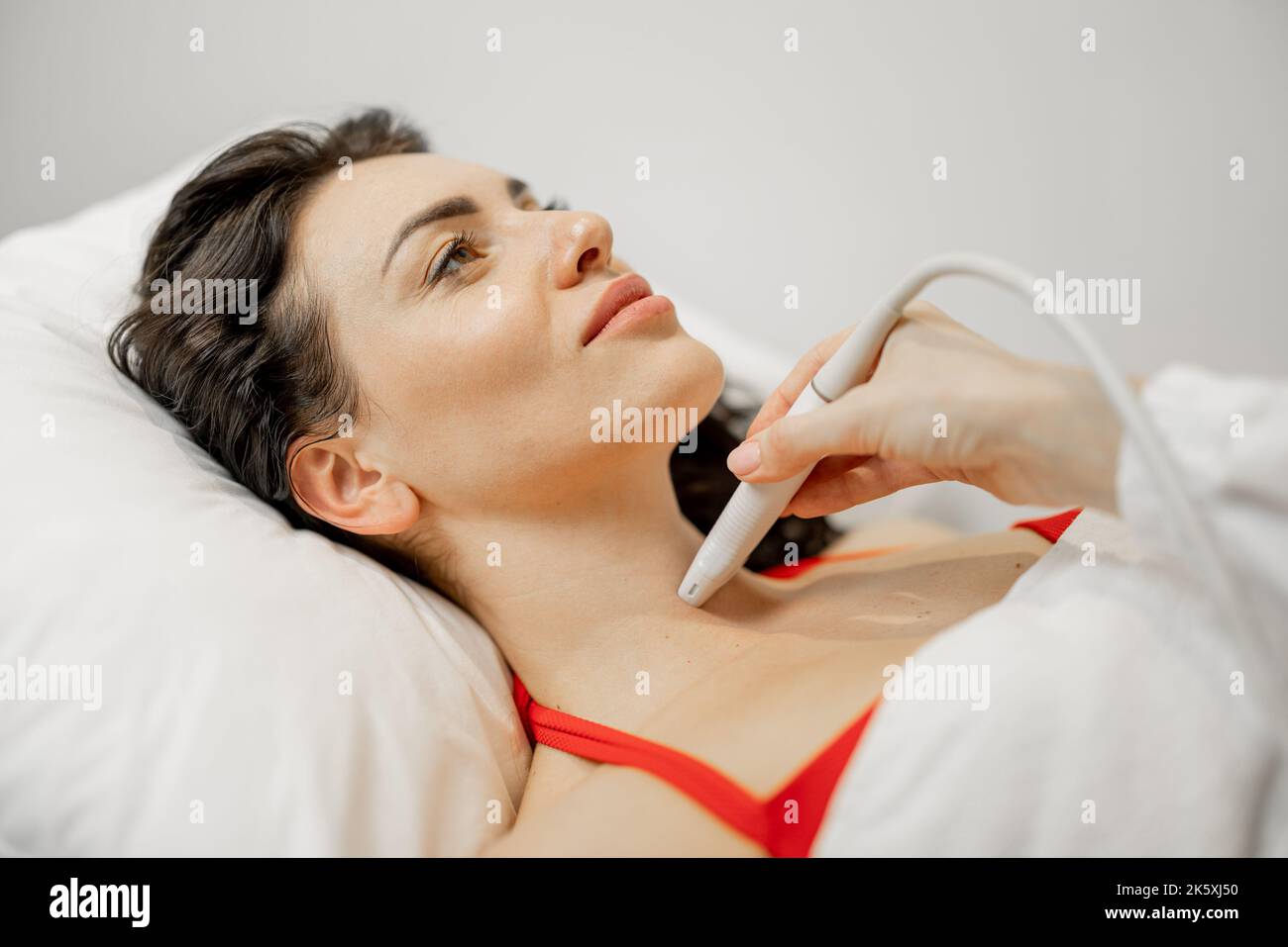 Frau untersucht Schilddrüse mit Ultraschall Stockfoto