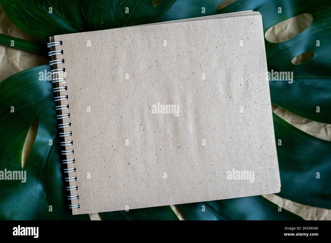 Leerer Spiralnotepad auf grünen Sommerblättern. Leere Papierseite Notizbuch, flach liegend, Kopierplatz Stockfoto