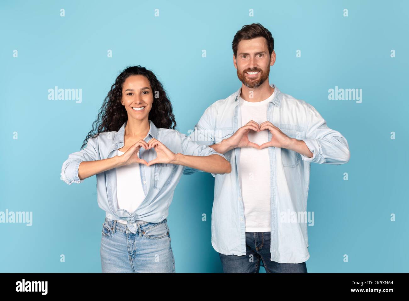 Fröhliche tausendjährige kaukasische und arabische Menschen haben Spaß zusammen, zeigen Herzzeichen in der Nähe der Brust Stockfoto