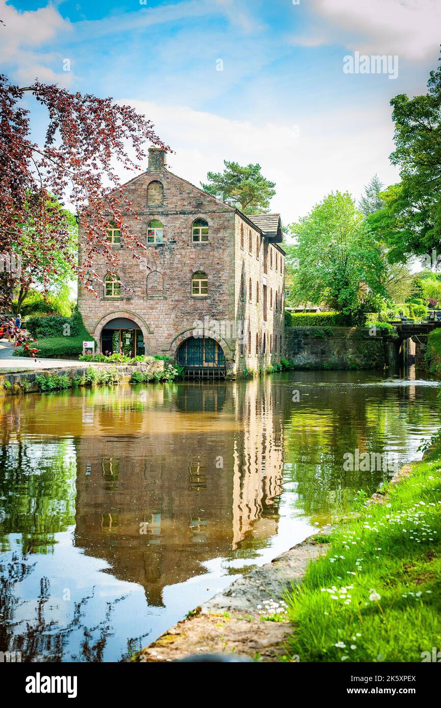 Eine vertikale Nahaufnahme eines alten Hauses neben einem See, umgeben von grünen Bäumen Stockfoto