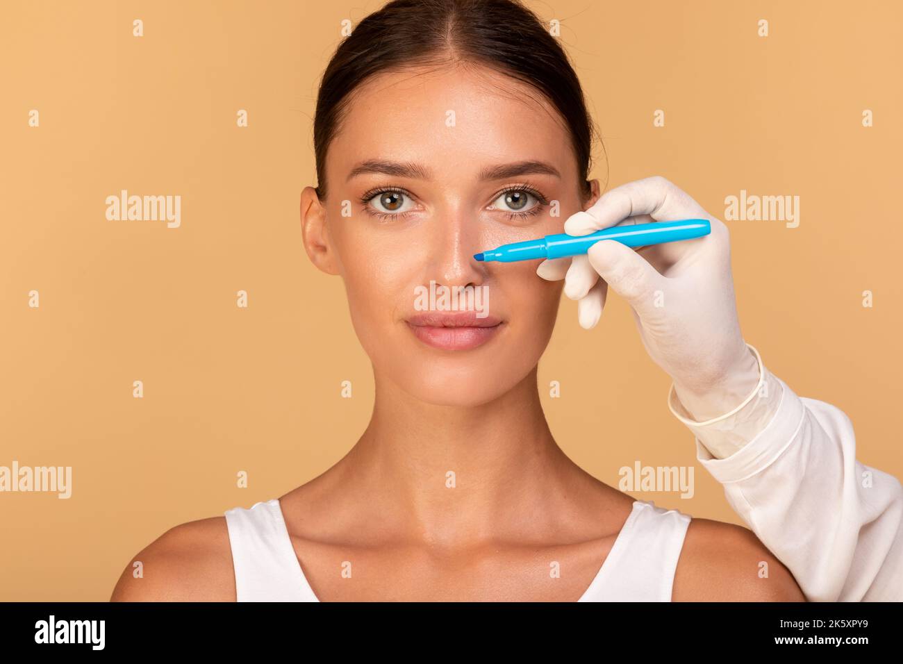 Rhinoplastik-Konzept. Arzt macht Spuren auf dem Gesicht des Patienten, junge kaukasische Dame bei Konsultation beim Chirurgen Stockfoto