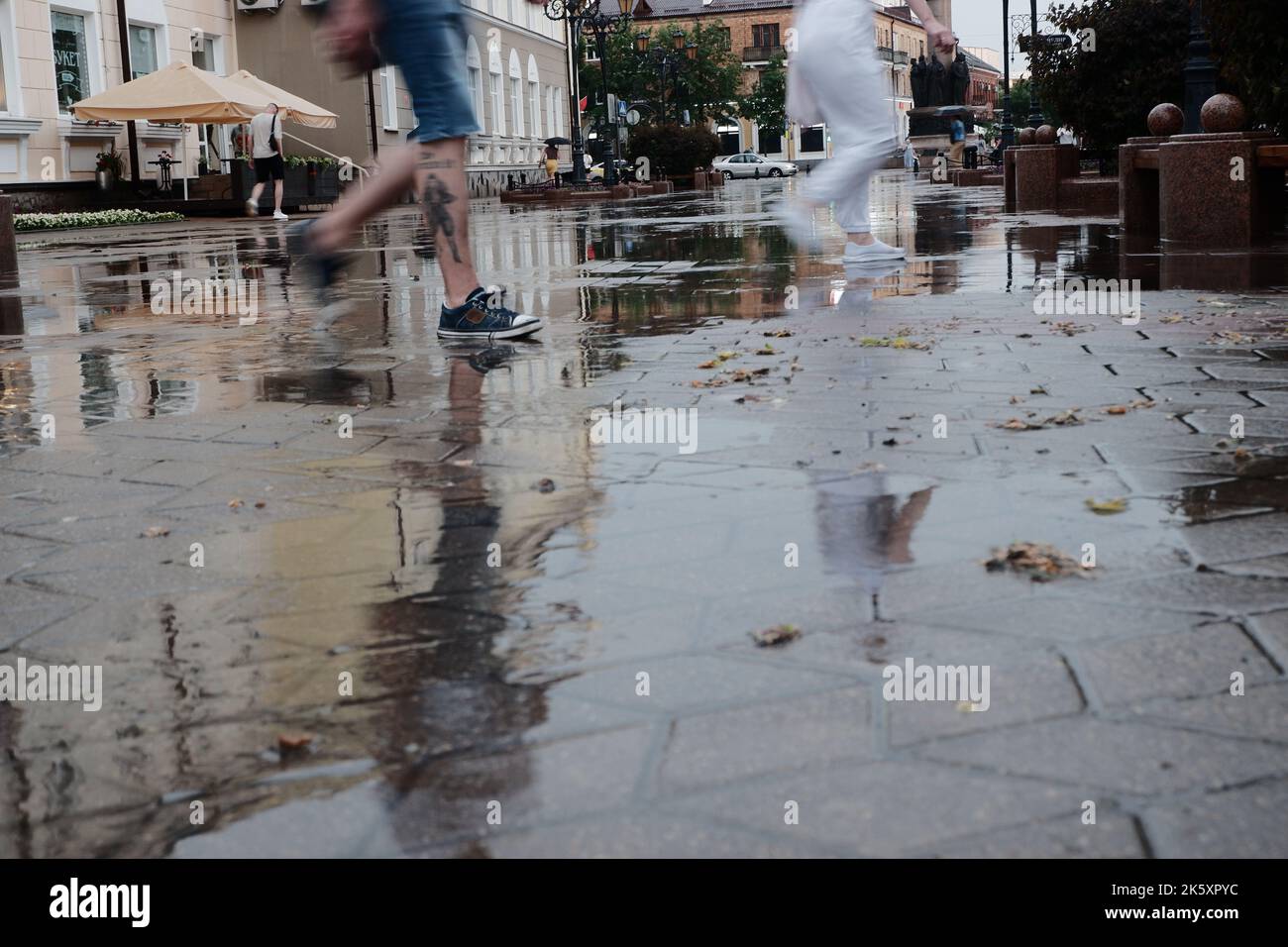 Straßen der Stadt nach starkem Regen. Barfuß auf Gehwegen mit Pfützen und Reflexionen Stockfoto