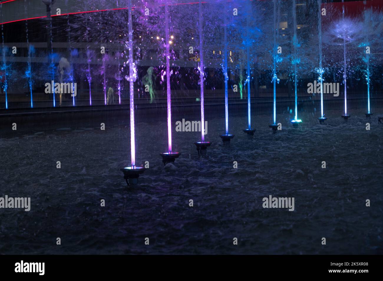 Mehrfarbiger Stadtbrunnen im Dunkeln an einem Sommerabend Stockfoto