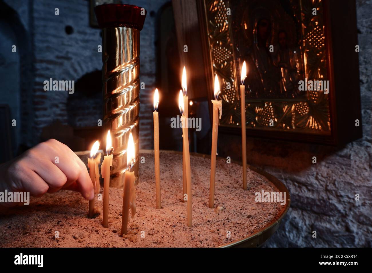 Gebet der Gläubigen in der Nähe des Altars einer christlichen Kirche. Kerzen anzünden Stockfoto