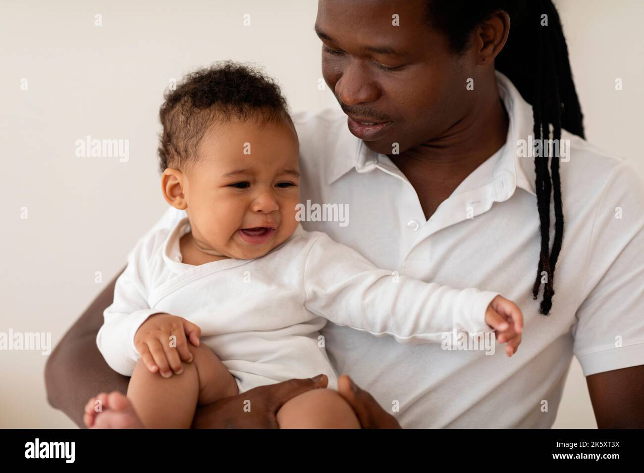 Portrait of Little Black Baby Crying in Father's Arms Stockfoto