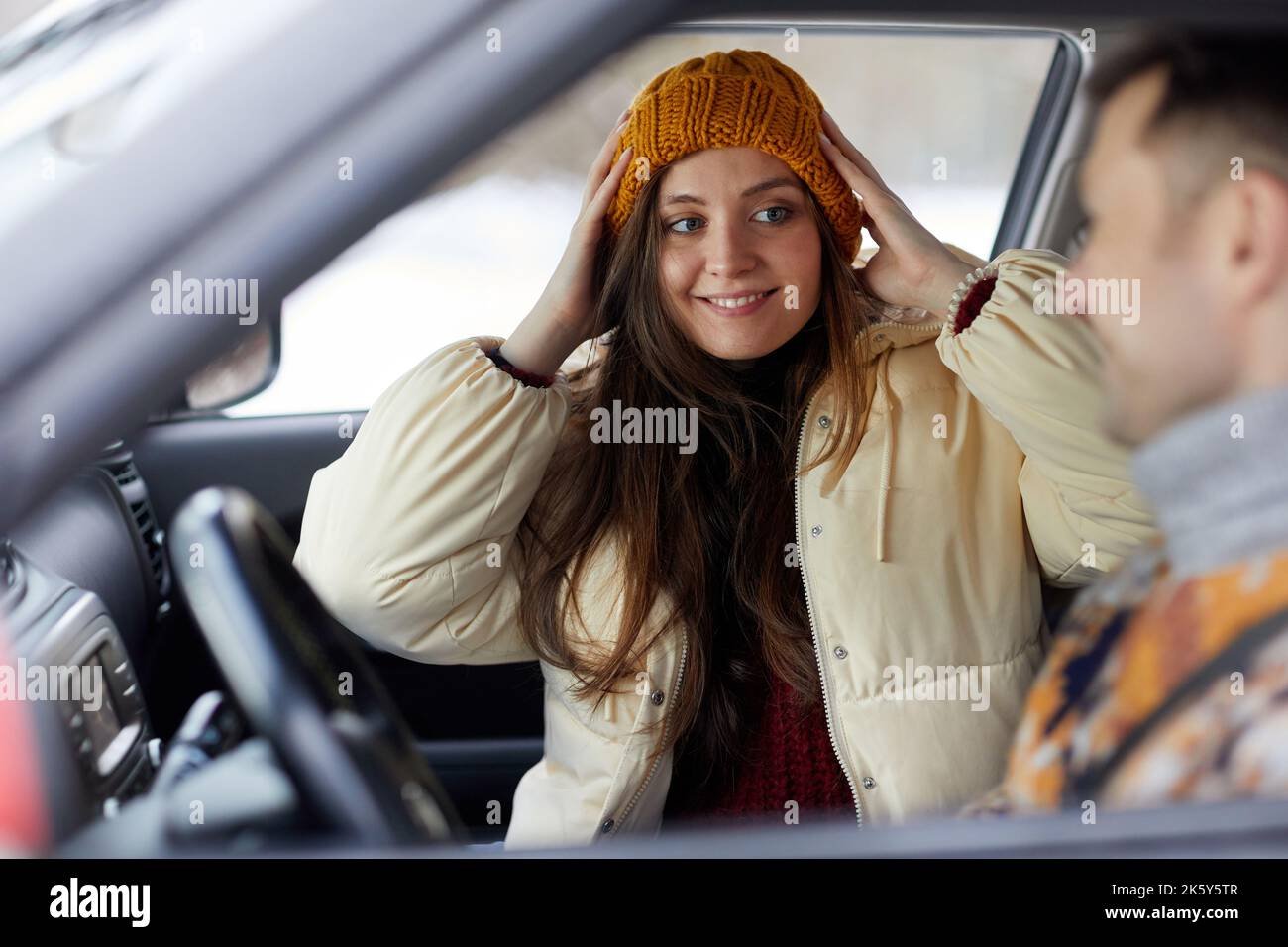 Porträt einer lächelnden jungen Frau im Auto mit ihrem Freund, bereit für einen gemeinsamen Winterurlaub Stockfoto