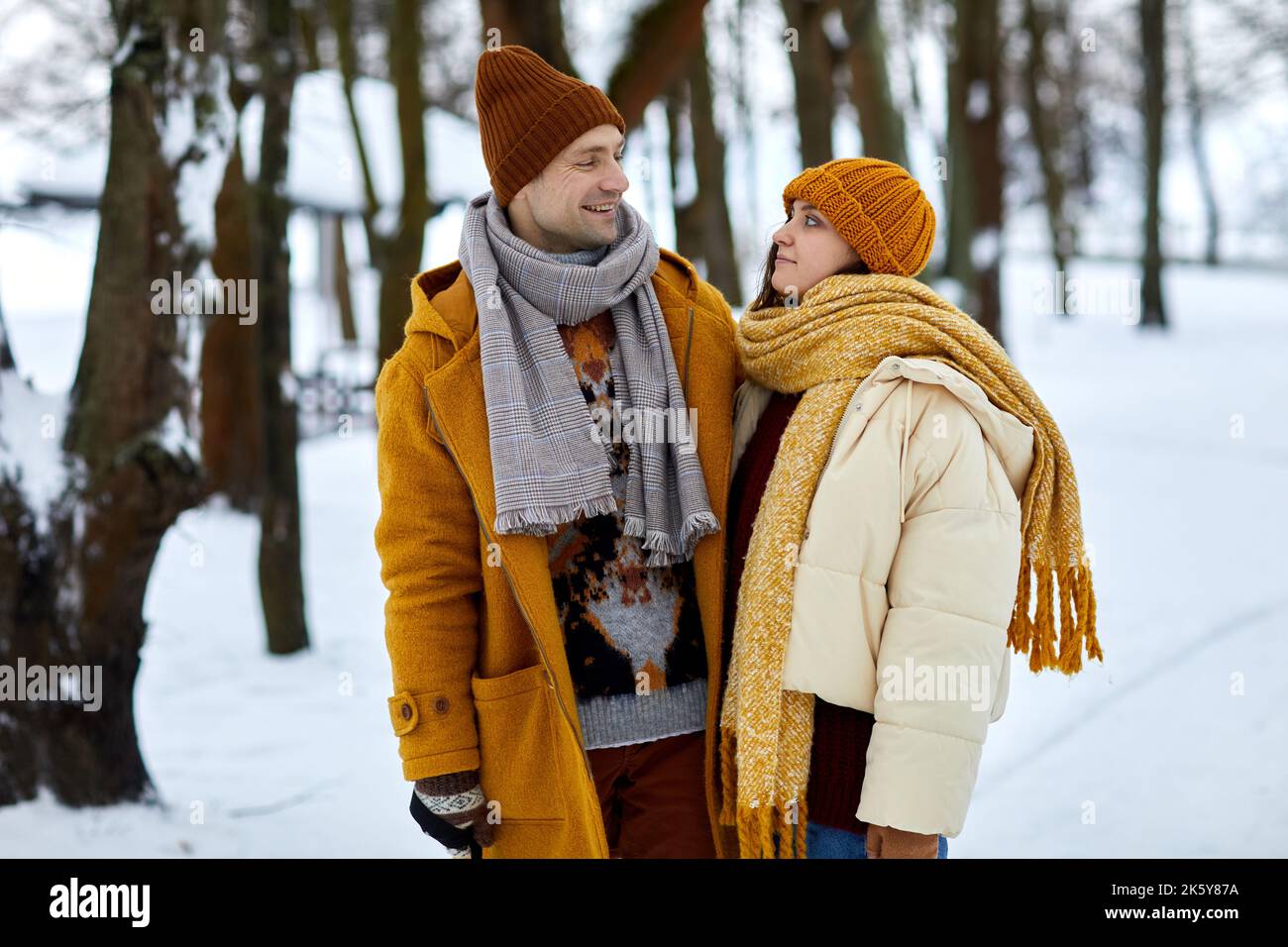 Waist-up-Porträt eines glücklichen Paares, das sich im Winterwald ansieht, während Sie in der Natur spazieren gehen Stockfoto