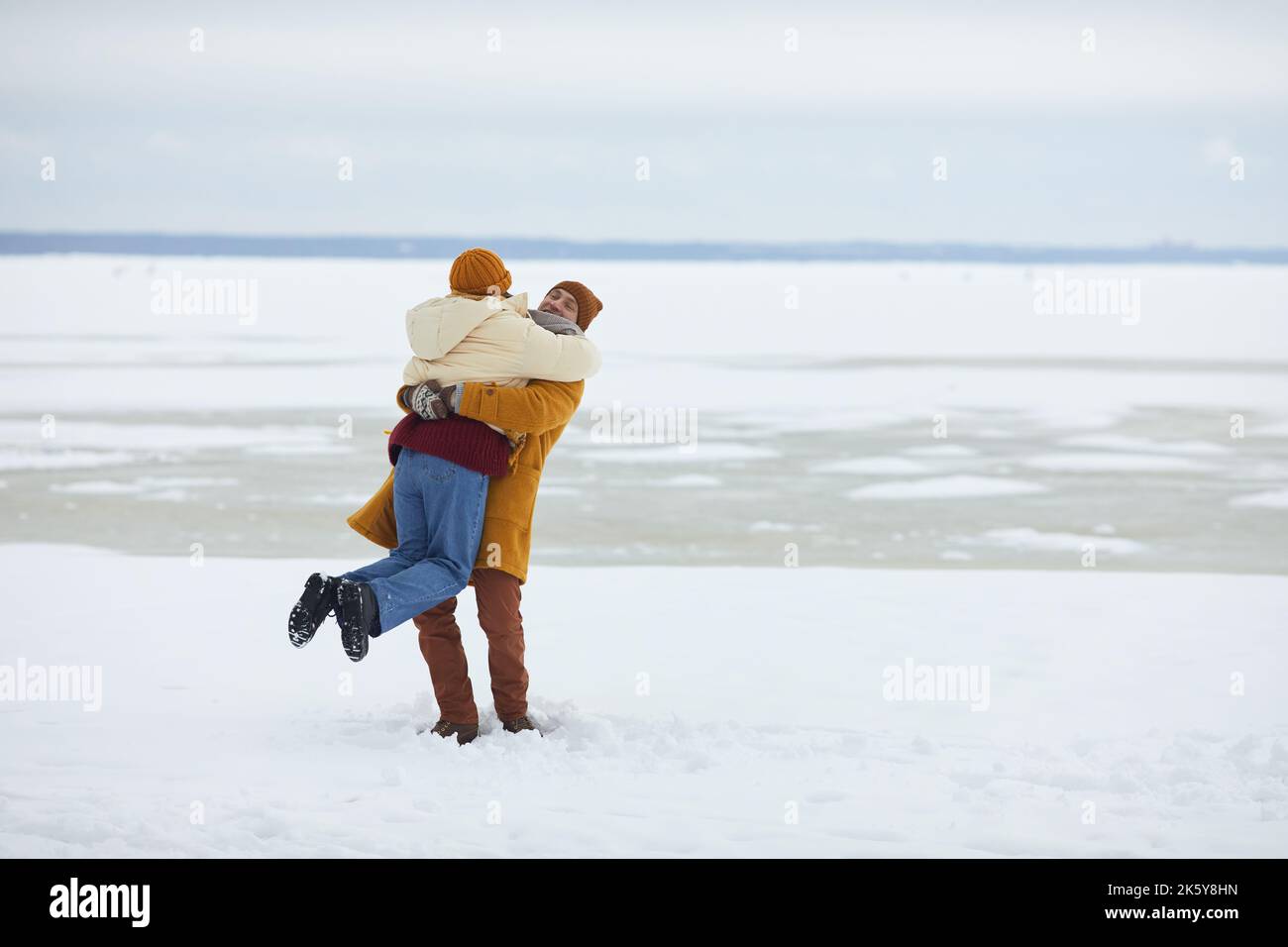 Porträt eines sorglosen jungen Paares, das sich in einer minimalistischen Winterlandschaft umarmt und Platz zum Kopieren bietet Stockfoto