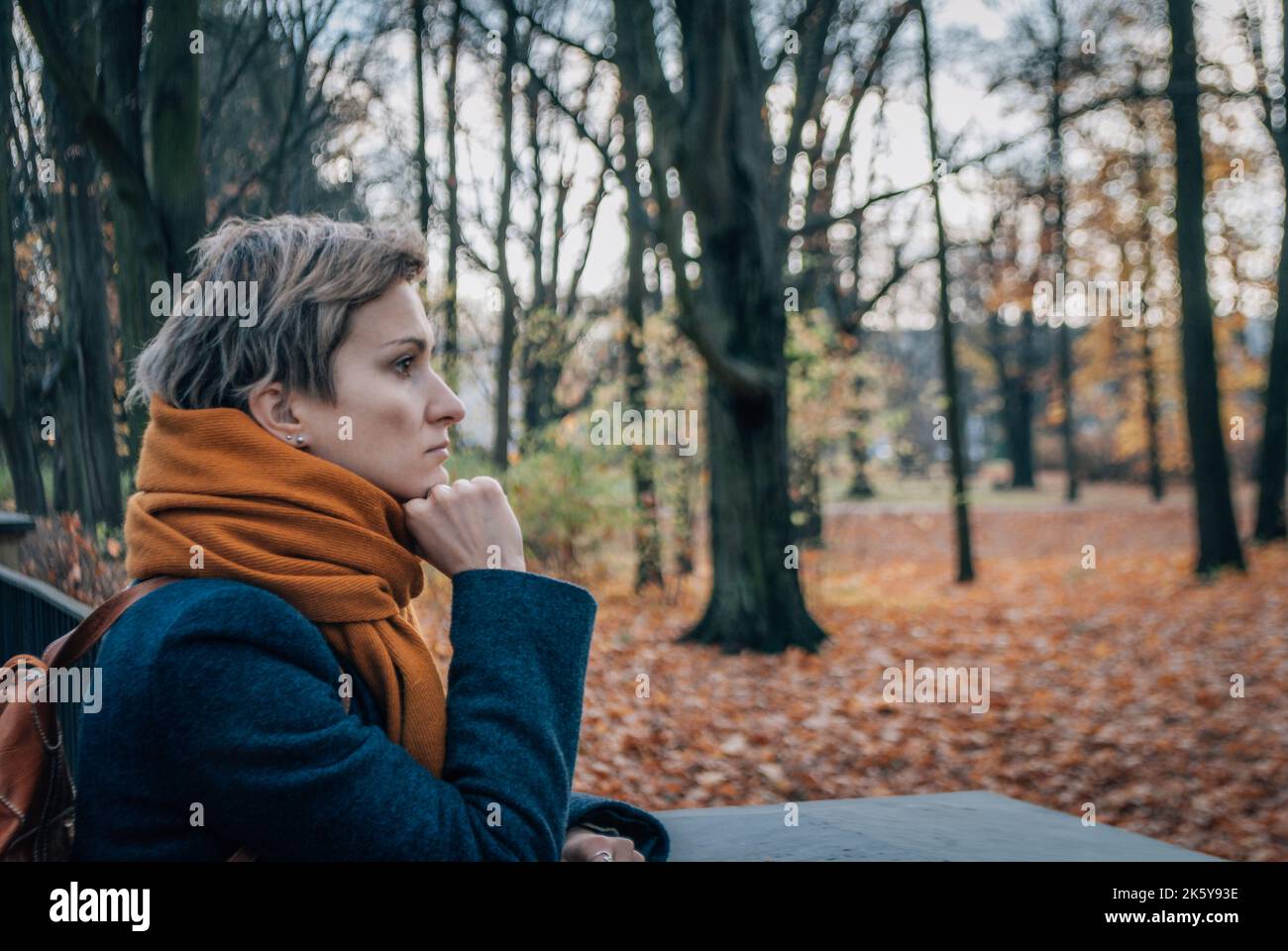 Ernst brütende kurzhaarige Blondine im Mantel und Schal im Herbst Stockfoto